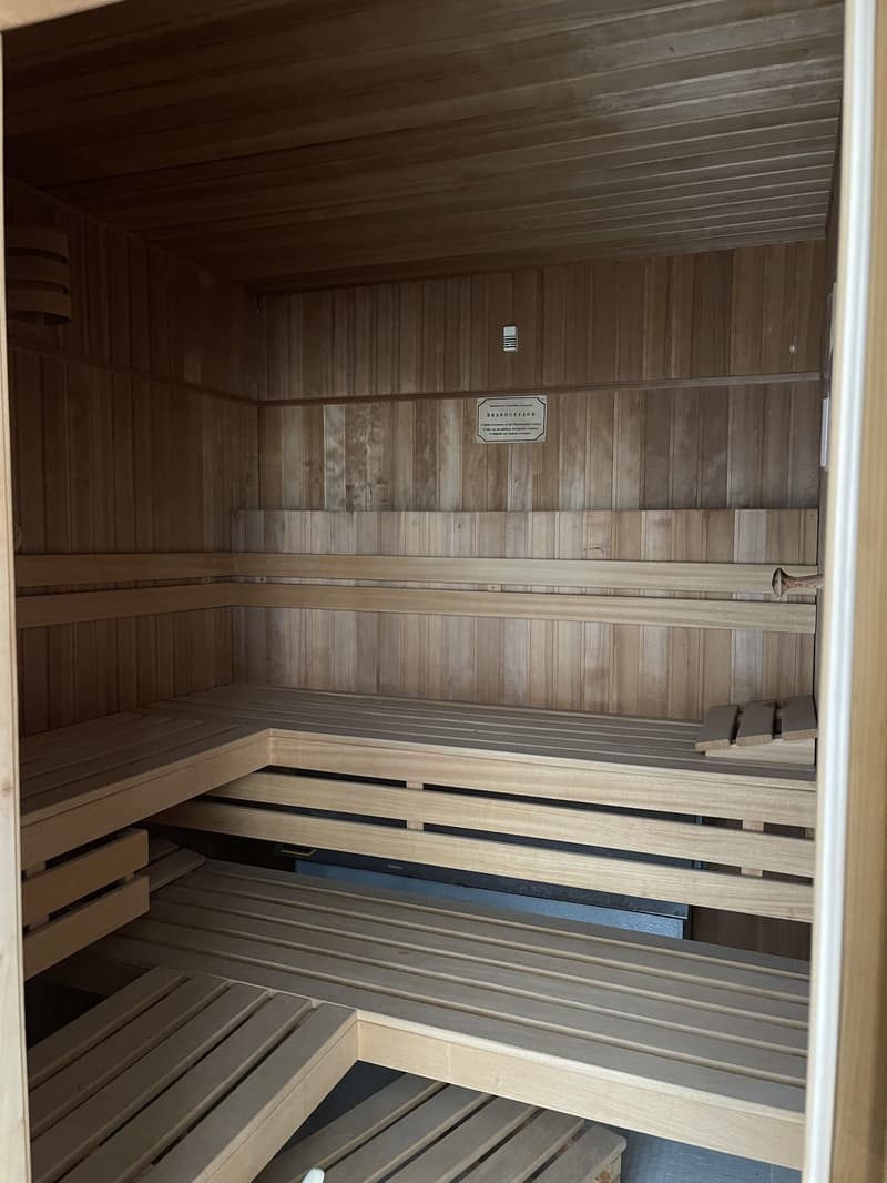 A wooden sauna room with benches and a sign on the wall.