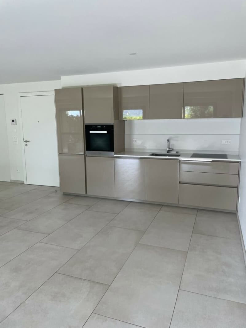 modern kitchen with white walls, stainless steel cabinetry, tiled flooring, integrated oven, double sink, neutral color scheme