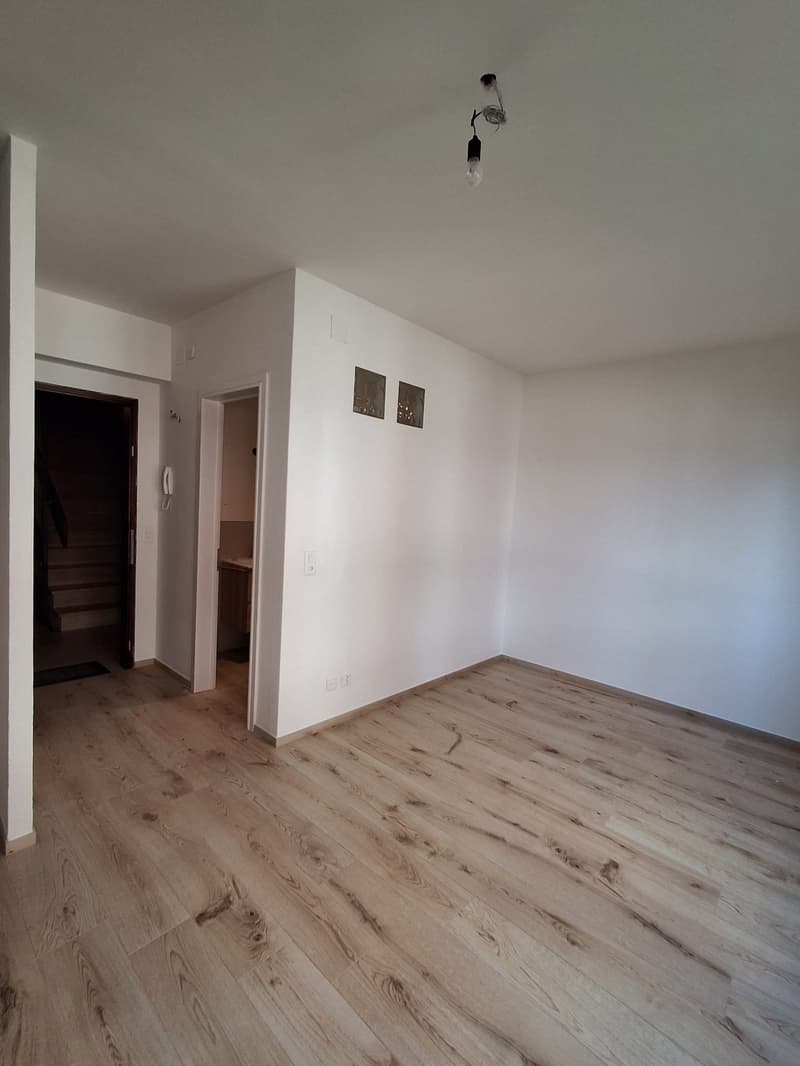 empty room, white walls, wooden floor, two open doors, one leading to stairs