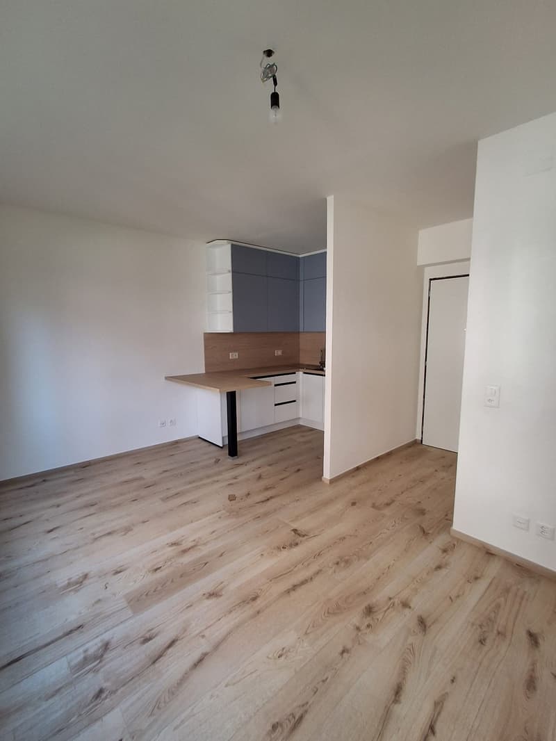 Open kitchen, wooden floor, white cabinets, dark gray walls, large countertop, light bulbs