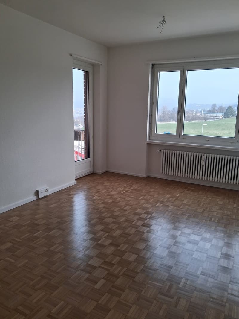 empty room, wooden floors, white walls, glass windows, heater on the wall, outlet on the wall