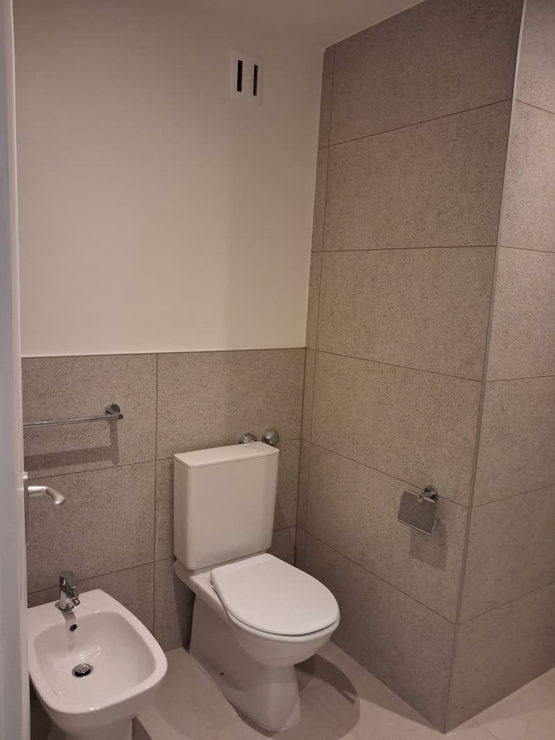 modern bathroom, white bidet, white toilet, tiled walls and floor, towel rack