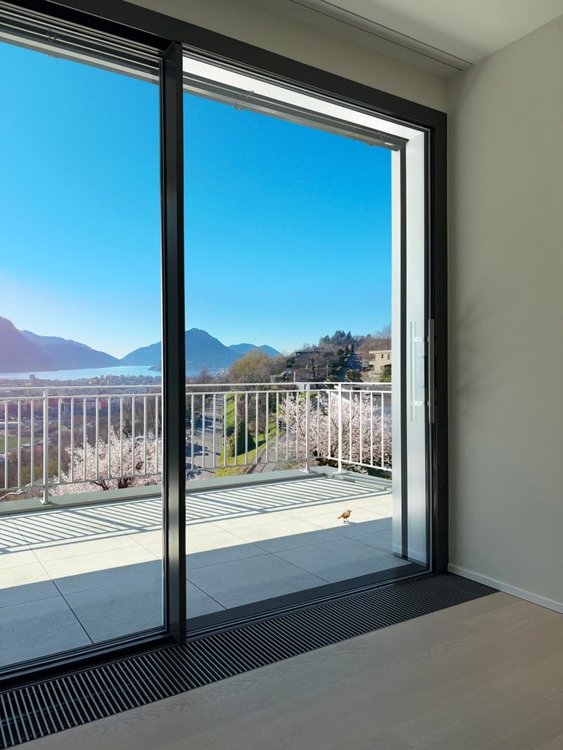 sliding glass doors, balcony, white railing, tiled floor, view of mountains and lake