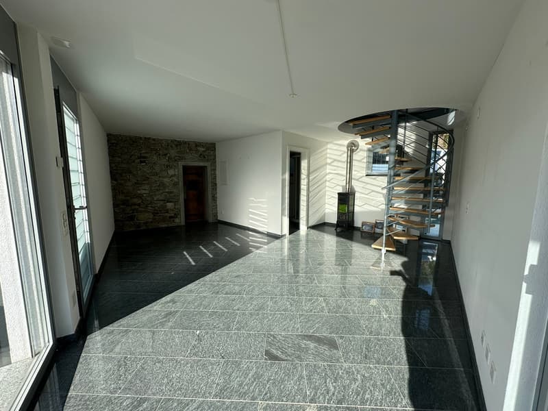 empty room with tiled floor, stone wall, staircase, large windows