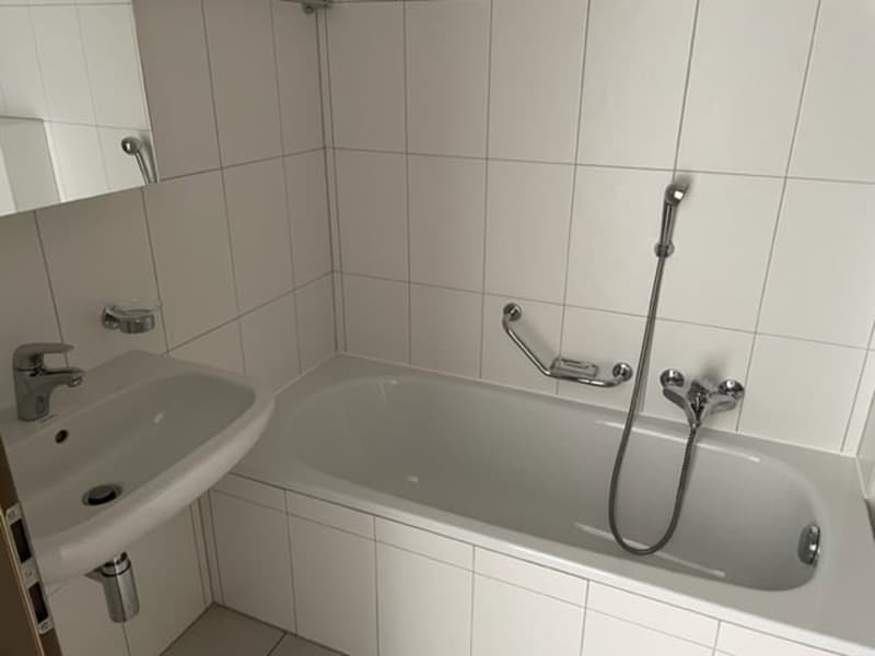 The image shows a bathroom with a white bathtub, a white sink, and tiled walls. The bathroom appears to be clean and well-maintained.