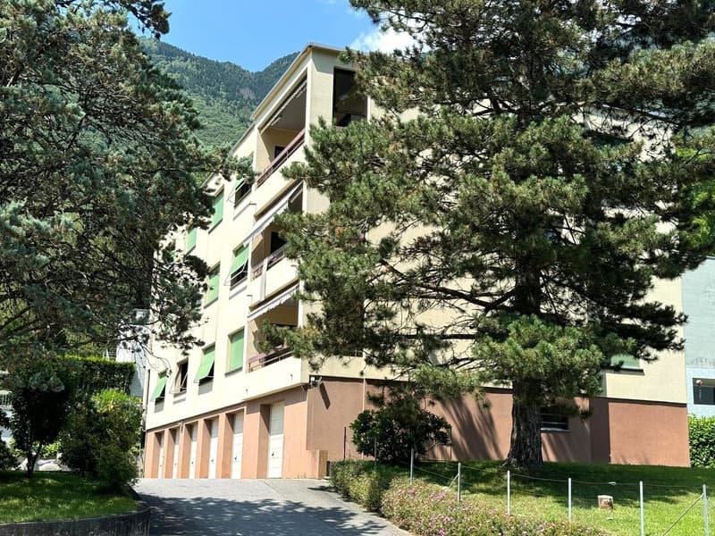 A building with 4 garages at the entrance, balconies on each floor, and several windows