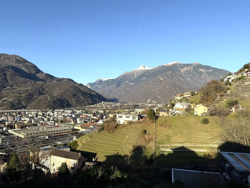 Town located in mountains, houses with different size, sunny day, snow on mountains