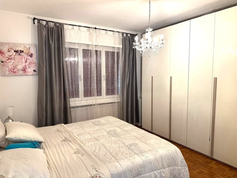 bed with bedding, wardrobe, table lamp, chandelier, window with curtains