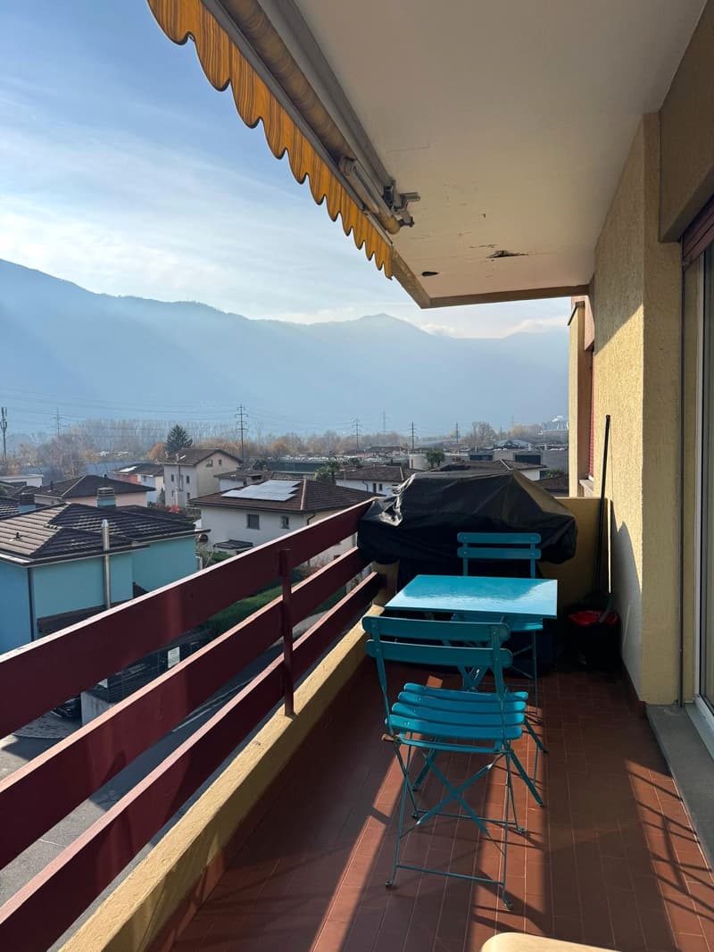 Balcony with a view, red railings, blue furniture, table and chairs, covered by awning, a grill cover, tiled floor