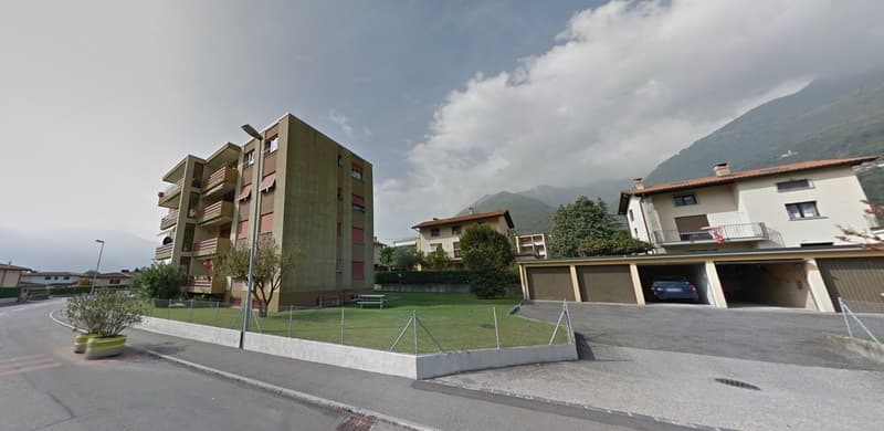 Apartment building with several balconies, a car parked in the garage