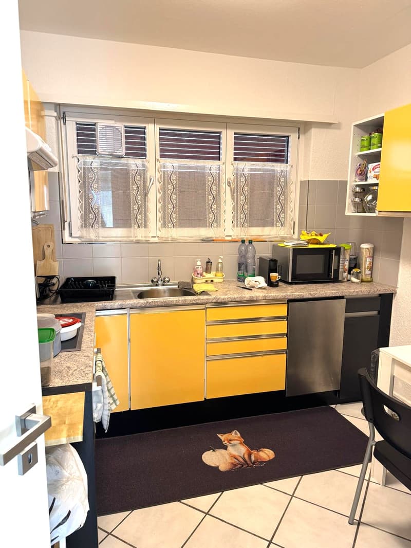 modern kitchen with yellow cabinets, granite countertop, undermount sink, stainless steel dishwasher, microwave, kettle, refrigerator, and window with curtains