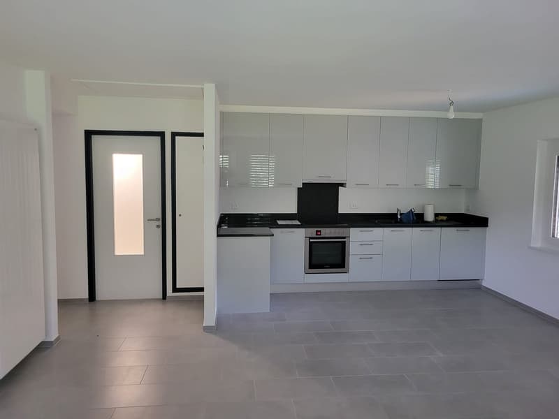 Modern kitchen with a sleek design and white cabinetry, black countertops, a gas range and oven, and built-in appliances.