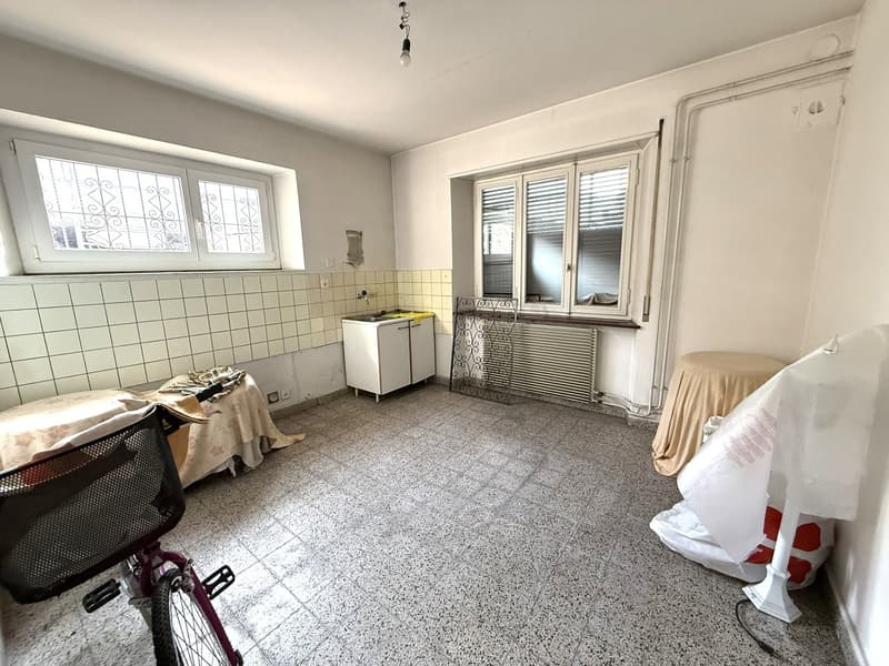Empty room with white tiled walls, windows, white cabinet, tiled floor, small bike