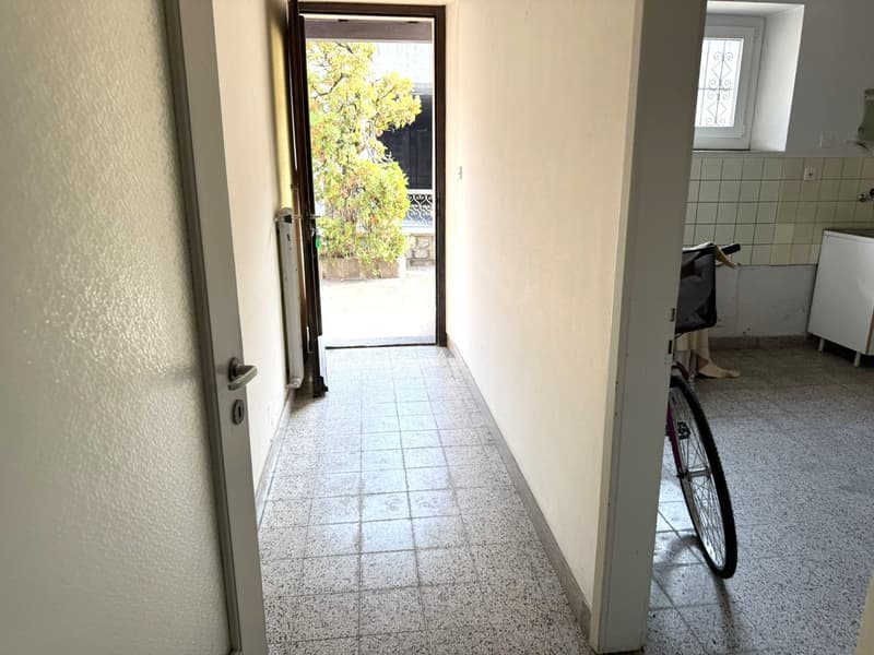 tiled hallway with white walls, open door, parked bicycle
