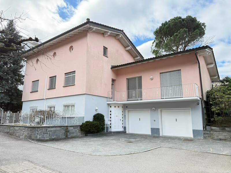Two-story house, pink and gray exterior, white doors, two garages, balcony, white fence