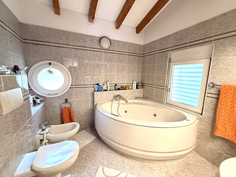 Modern bathroom with a large bathtub, a window, a toilet, a bidet, and a sink.