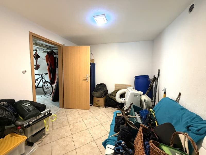 Storage room with wooden door, bicycle, storage boxes, bags, and various items