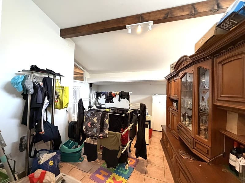 laundry room with clothes hanging, drying rack, storage boxes, wooden cabinet, refrigerator, lamps