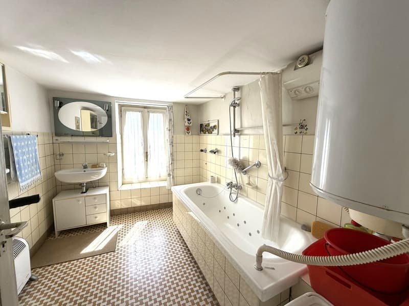 Bathroom with bathtub, sink, mirror, and tiled walls