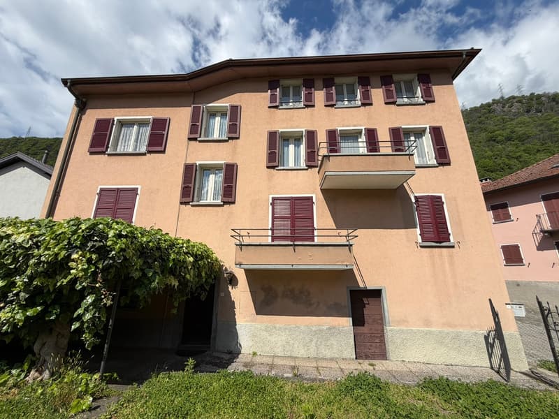 3 story building, beige exterior, red shutters, balcony, garage, green vegetation