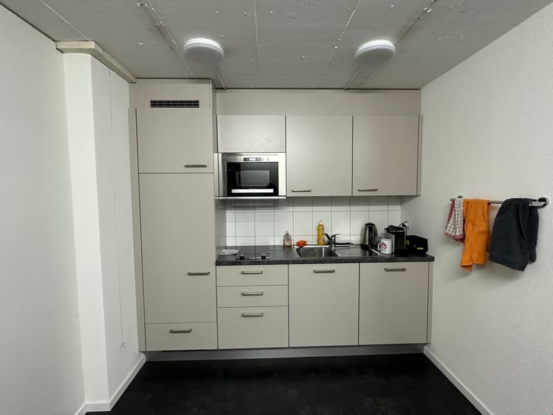 kitchen with kitchen appliances, microwave, cabinets, and a white tiled wall
