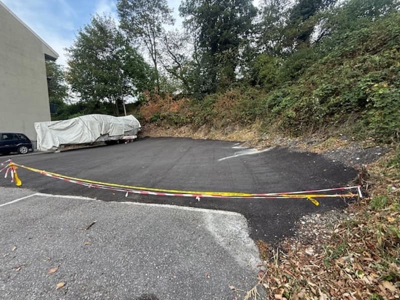 Parking lot with a covered trailer, a parked car, and caution tape marking off an area.