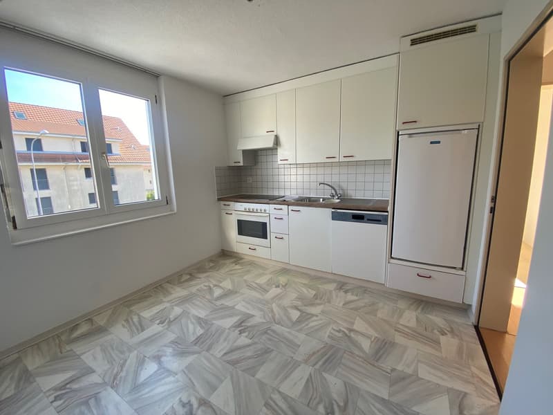 Modern kitchen with white cabinets, marble tiled floor, and stainless steel appliances including a refrigerator, oven, and dishwasher.