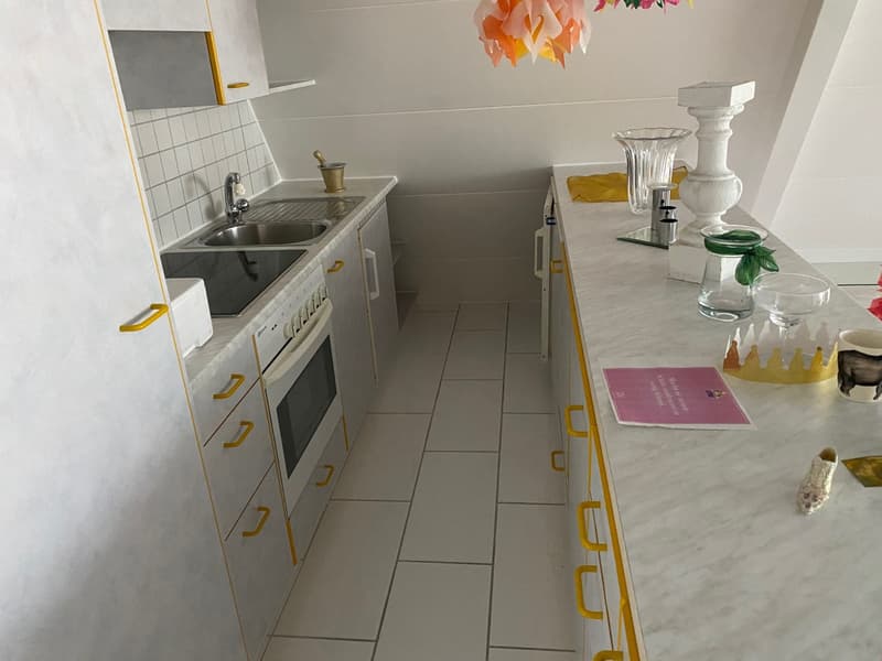 Compact kitchen with white cabinets, yellow accents, tile flooring, sink, and a dishwasher