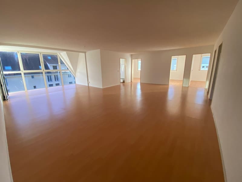 Empty room with wooden floor, large windows, two small windows in the room, hallway, white walls,