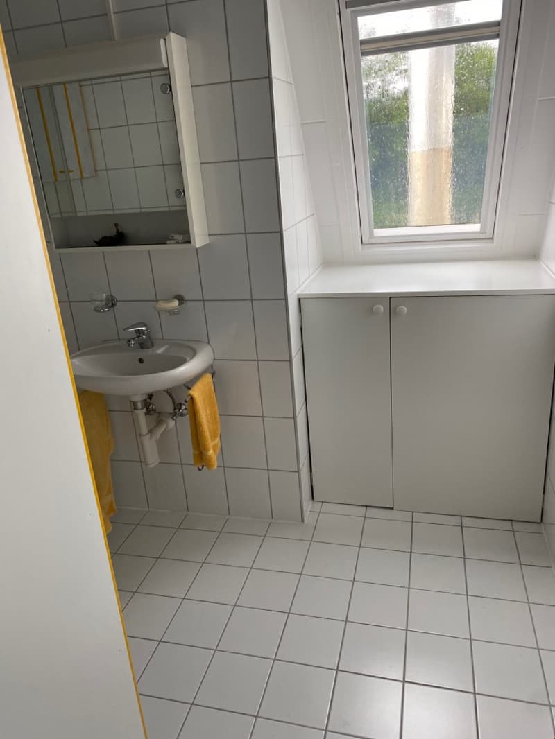 Tiled bathroom with a sink, mirror cabinet, and a window
