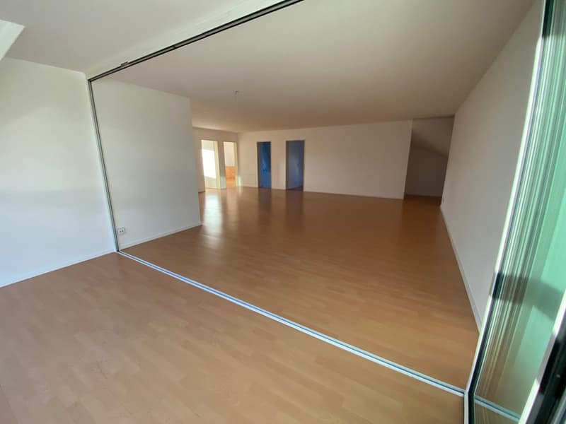 large empty room, wooden floor, white walls, large glass door leading to balcony