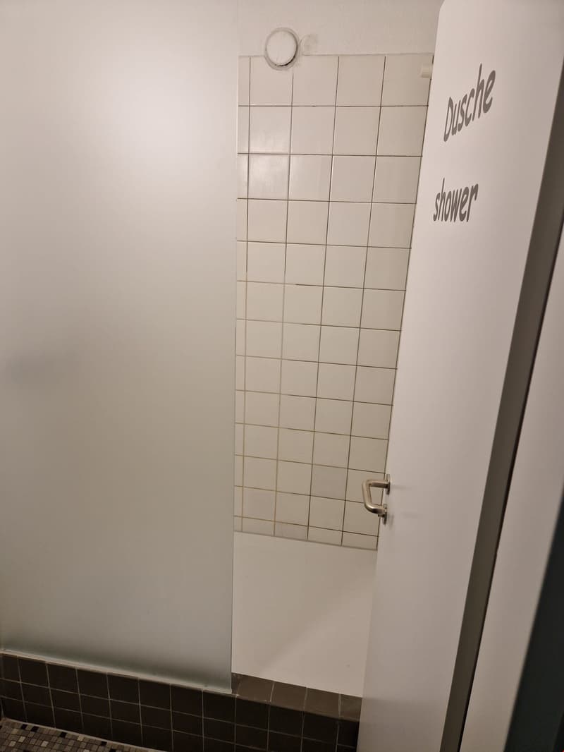 Tiled bathroom with a shower stall and a mirror on the wall