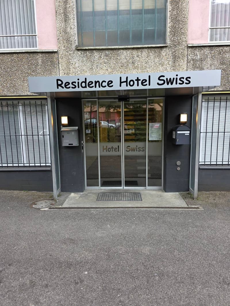 Entrance to Residence Hotel Swiss with glass doors, signage, and mailboxes.