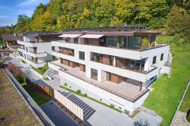 Modern 2 story apartment building, white and brown exterior, multiple balconies, solar panels