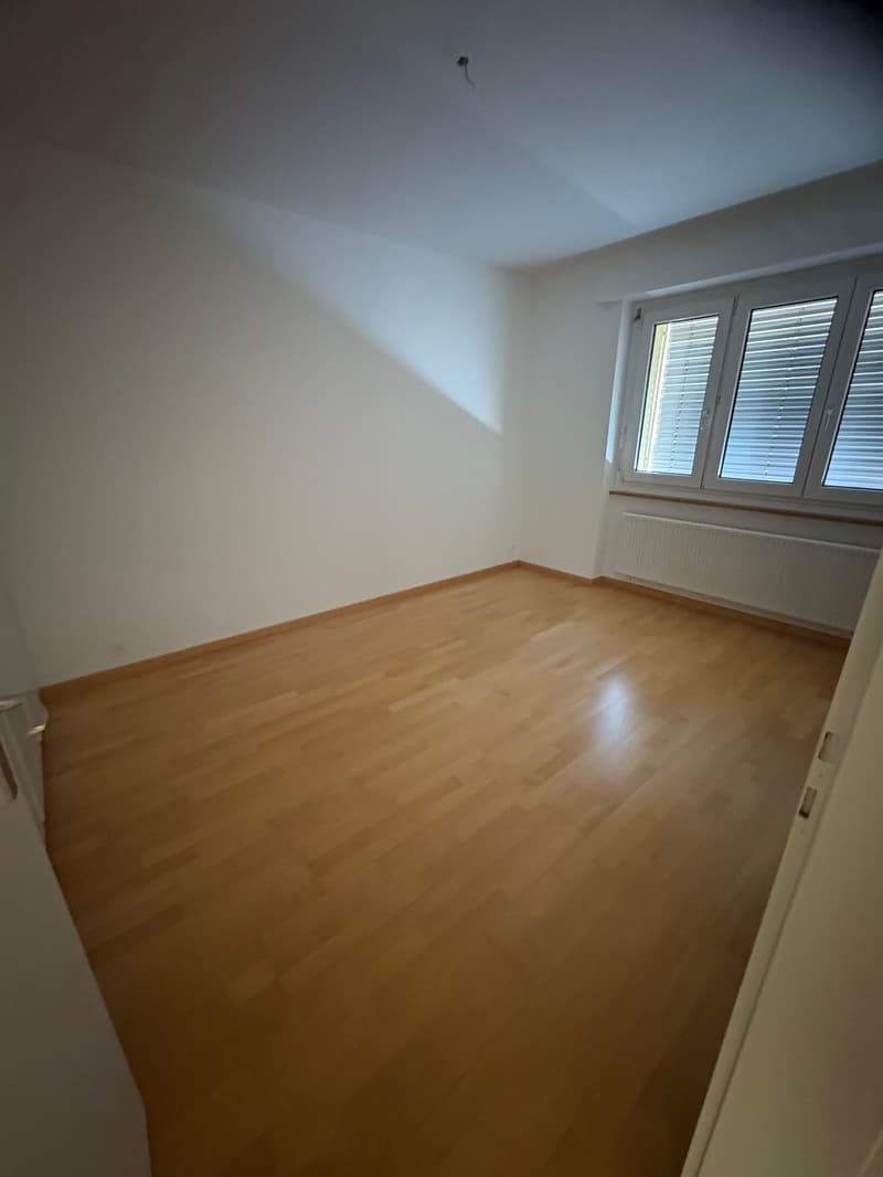 empty room with wooden floor, white walls, window with white shutters