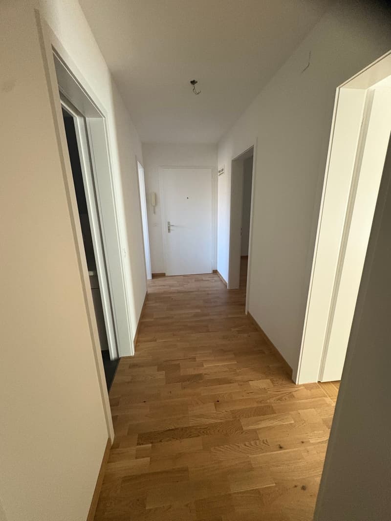 empty hallway with wooden floors and white walls