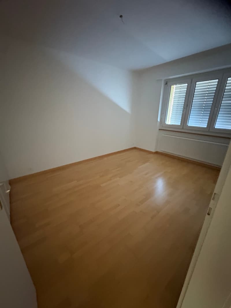 empty room with wooden floor, white walls, windows with blinds