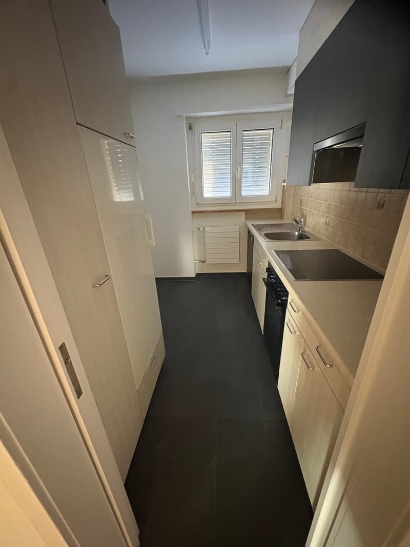 empty kitchen with double sink, gas stove, cabinets, and windows