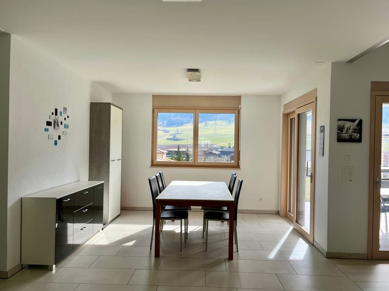 Spacious dining room with large windows offering a scenic view, wooden dining table and chairs, built-in cabinet, and tiled flooring
