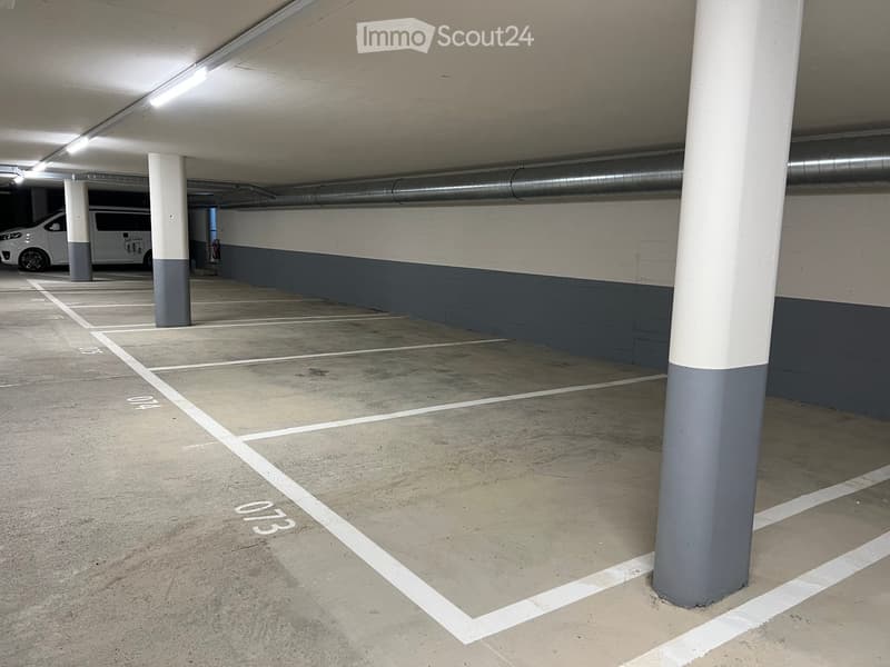 underground parking lot, white walls, grey pillars, empty parking space, and white marking lines