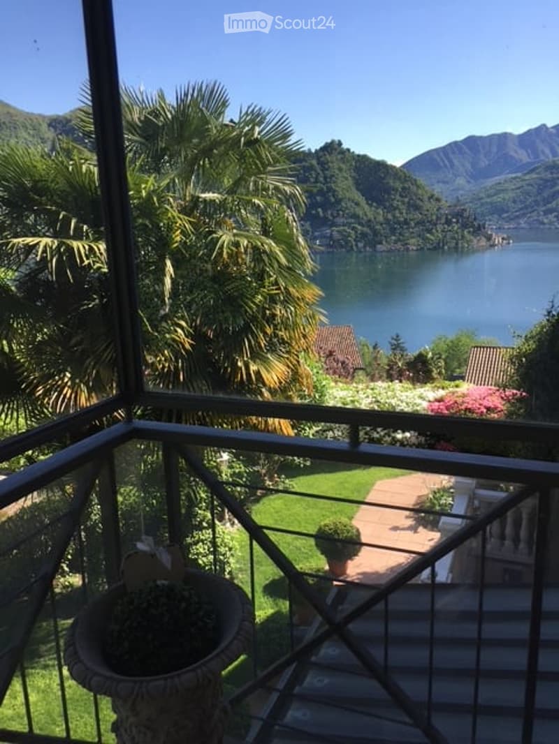 Balcony view with a lake, mountains, and landscaped garden with plants