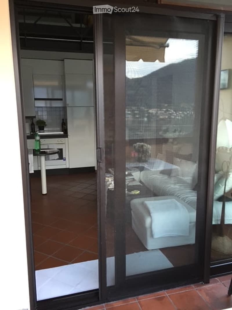 a sliding glass door opens onto a balcony, living room with couch, white ottoman, and coffee table