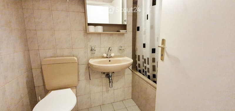 tiled bathroom with toilet, sink, bathtub, mirror, towel rack
