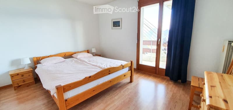 Two beds, wooden bed frame, white linen, wooden nightstands with lamps, picture frame, sliding glass doors, curtain