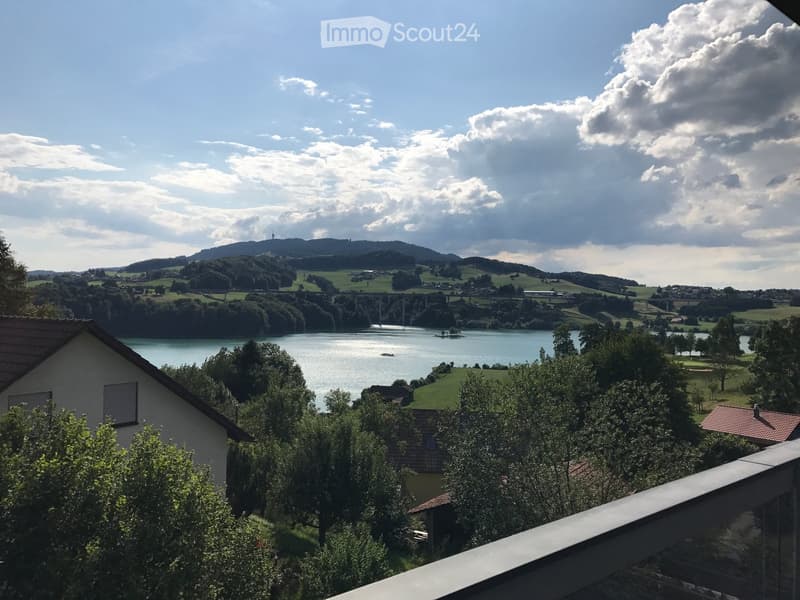 House with brown roof, overlooking a lake and hills