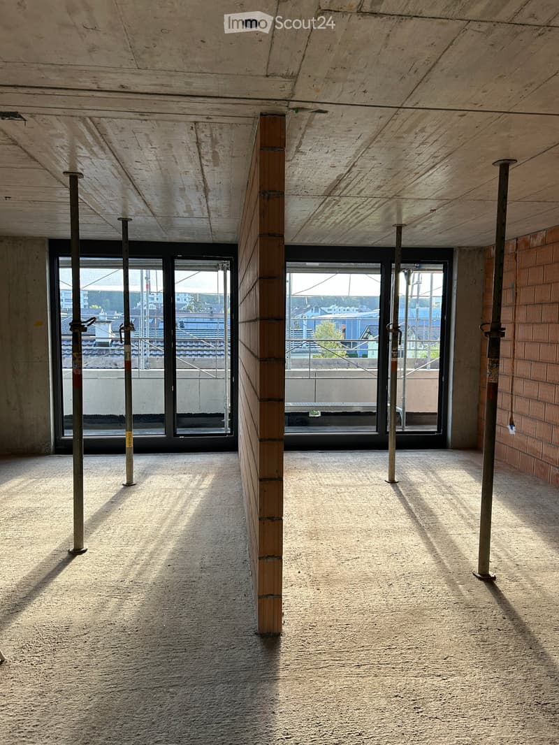 Empty room with exposed wooden ceiling, concrete floor, and large windows showing an outdoor view. No furniture or equipment present.