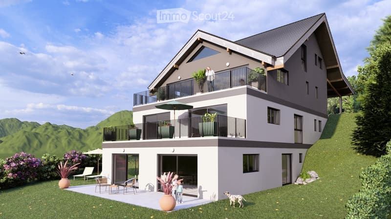 3-story modern house with gray exterior, large balconies, and a patio area with outdoor furniture. The house is surrounded by lush greenery and mountains in the background.