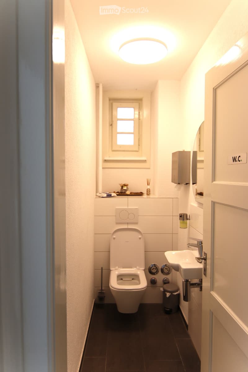 small white bathroom with white toilet, sink, and white tiled floor.