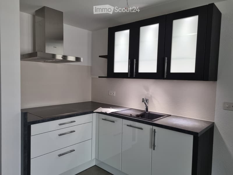 White cabinets, glass doors, modern appliances, black countertops, range hood, faucet, white walls, power outlets