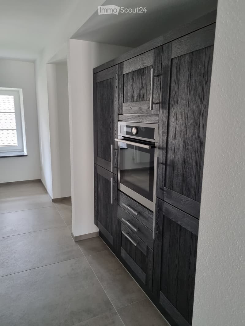 wooden cabinets, tiled floor, modern stove, open space with a window, clean and minimalist design